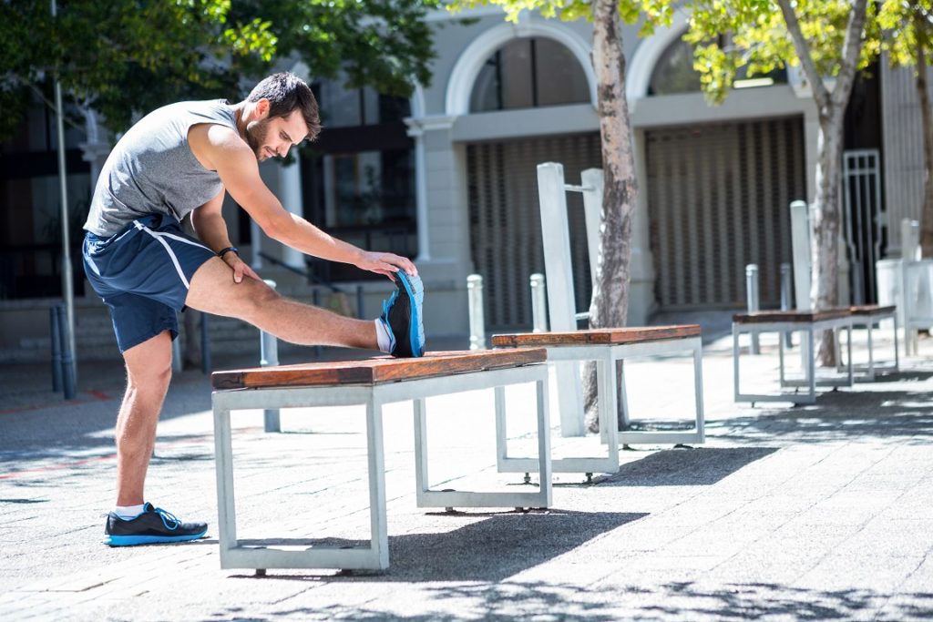 man stretching leg on outdoor bench